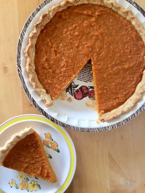 Sweet potato pie with a slice on a serving plate.