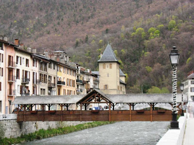 Covered wooden bridge and church with mountain slope behind