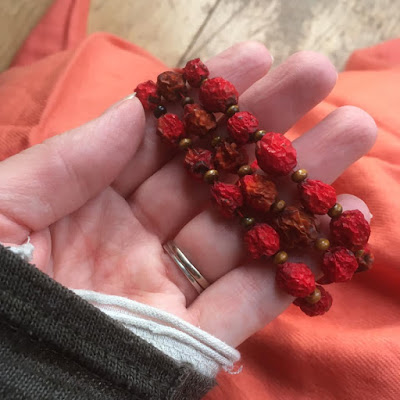 Woman's hand with a rowan necklace wrapped around her fingers