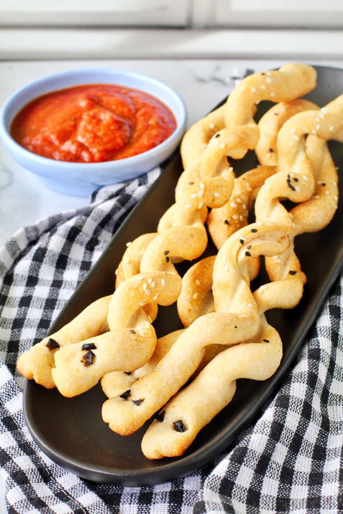 Breadstick Snakes on a black plate with dipping sauce.