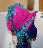 hat with pink body of hat re-shaped and re-formed with blue woven ribbon around it and coming out of top and hanging below hat on side