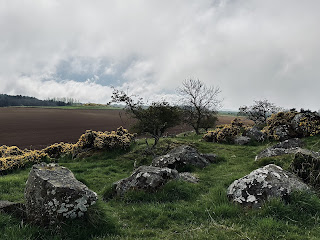 a photo showing a hilly area with some rocks on it and a ploughed field in the background.  Photograph by Kevin Nosferatu for the Skulferatu Project.