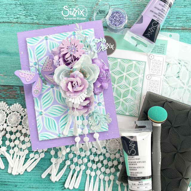 Aqua and purple mixed media panel created with Sizzix creamy matte acrylic paints, defined petals embossing folder and layered stencil, patterned butterflies die, Tim Holtz vault wildflowers die set; Prima Marketing Aquarelle Dreams flowers; Pinkfresh Studio Jewels; and lace.