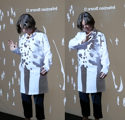 Alison Humphrey in a lab coat playing the full-body videogame Shadowpox: The Antibody Politic at the 70th Assembly of the World Health Organization