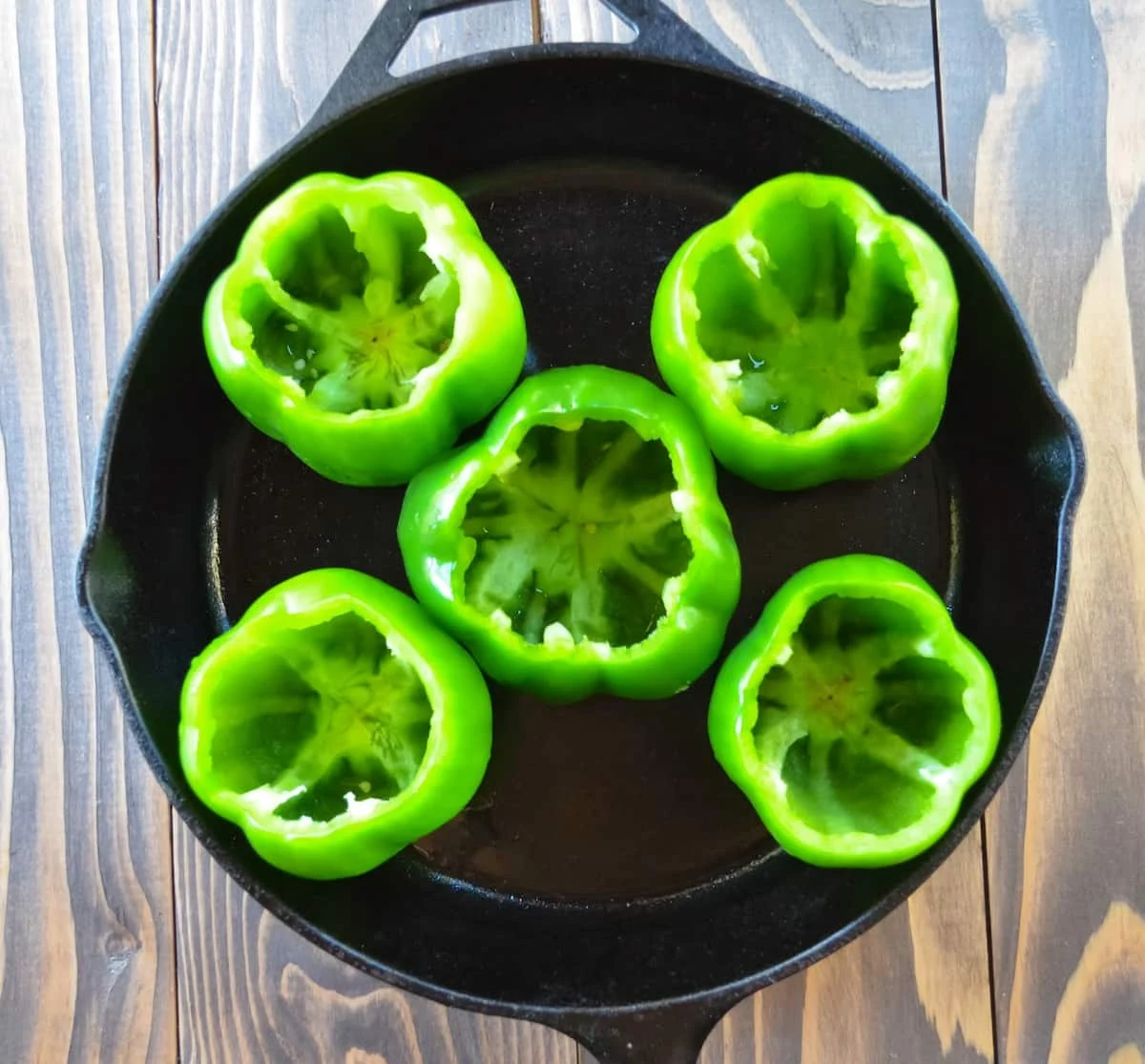 5 Bell Peppers with tops and seeds removed in a cast iron pan.