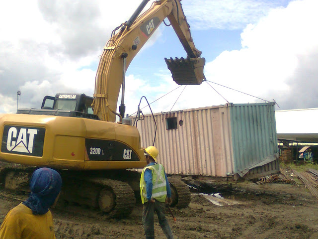 backhoe lifting the container van