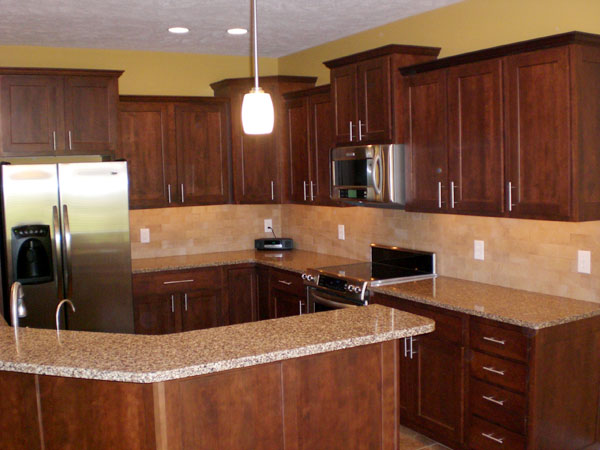 Cherry kitchen cabinets with light countertops and backsplashes