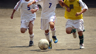 スパイクを履きボールを追いかけるサッカークラブの児童たち