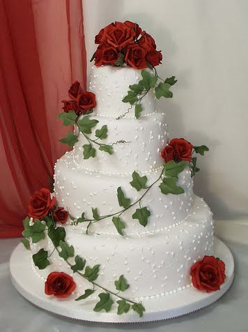 Elegant round wedding cake with edible pearls and topped with red roses on 