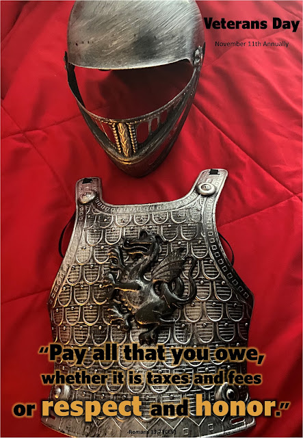 A toy helmet and breastplate atop a red quilt make up the background. Text overlay quotes Romans 13:7 and reminds that Veterans Day is on November 11th annually.