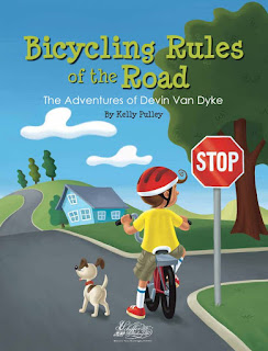 Book cover, 'Bicycling Rules of the Road' by Kelly Pulley. Image depicts boy in helmet on his bicycle, shown from the rear view, paused in a roadway next to a stop sign. The boy's head is turned right, looking down a side street that intersects the road he is on. The road is lined with green landscaping, a single blue house and trees. A dog stands in the road next to the boy, looking ahead.