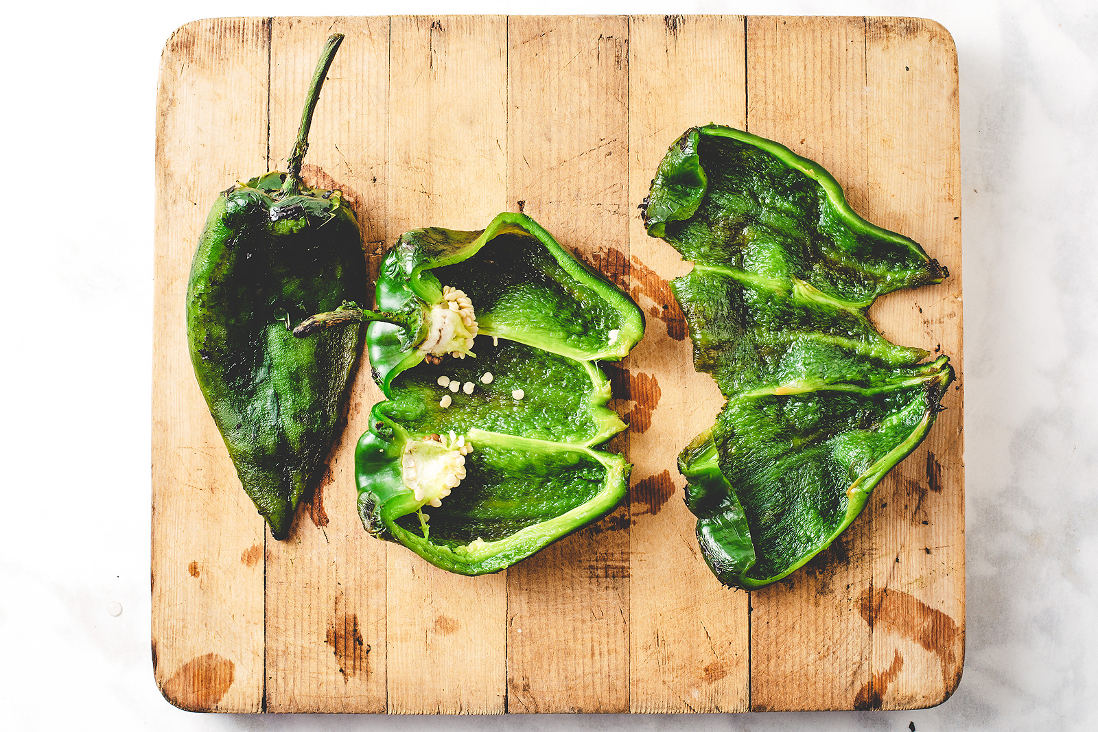 The steps to removing seeds from a roasted poblano pepper.