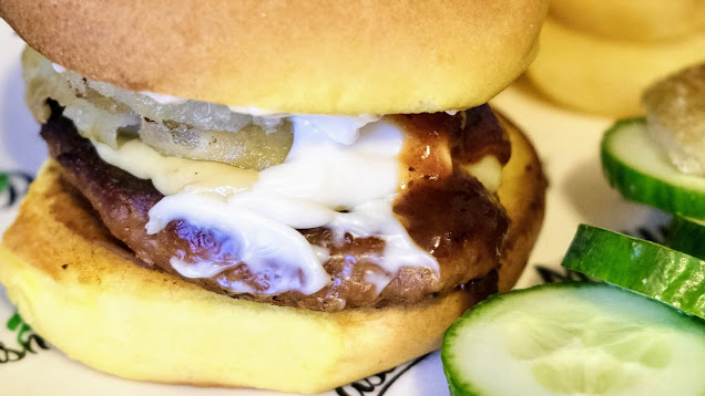 Vegan burger in a roll with vegan onion rings, vegan mayo and BBQ sauce