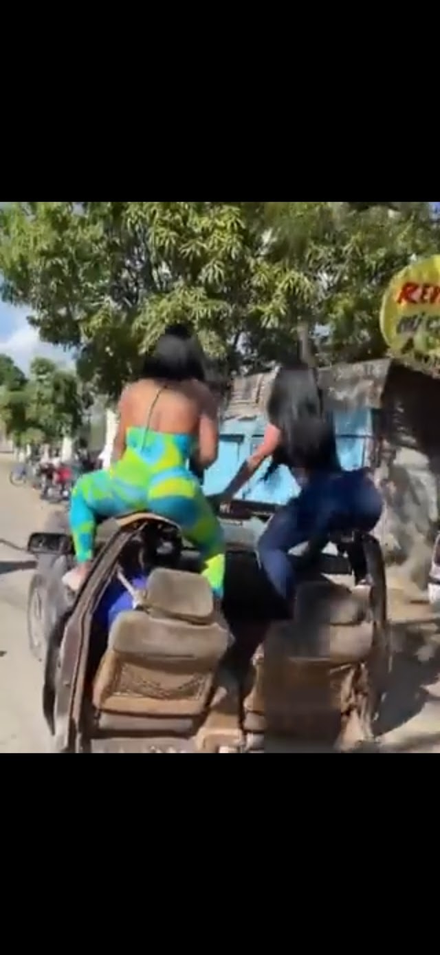 Dos mujeres arriesgando su vida en  encima de una camioneta con dos ruedas,; muy felices al igual que el conductor 