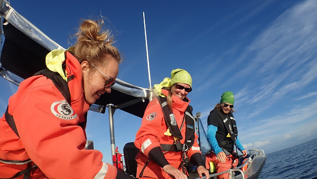 3 team members, smiling on a boat. 