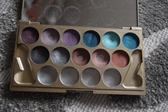 An eyeshadow palette with 11 shades. 4 are showing the bottom pan due to use.