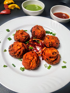 Serving tandoori momos in a garnished plate, green chutney and tomato sauce in background
