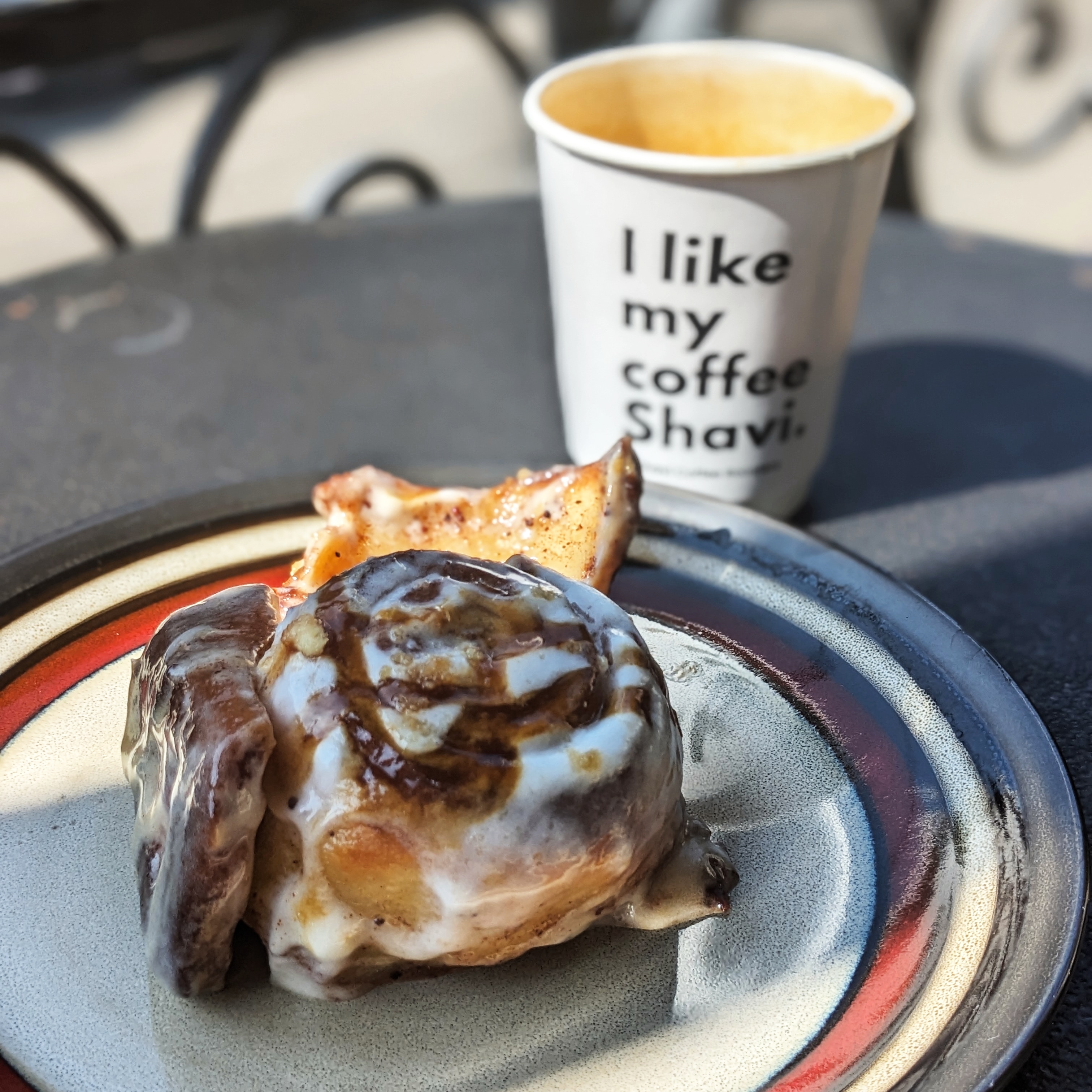 An iced cinnamon bun and a flat white in a take-out cup from Shavi Coffee Roasters, one of the best cafes in Tbilisi