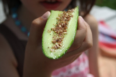 Enfant croquant dans une tranche de concombre garnie de zaatar