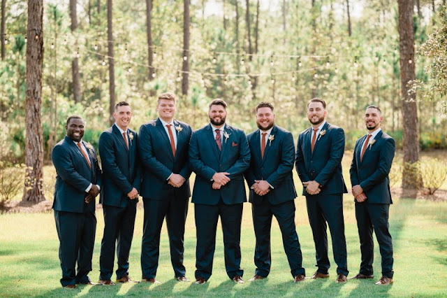 groom standing with groomsmen in navy suits with rust ties