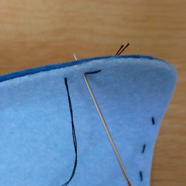 Working a backstitch on to blue felt fabric along the edge