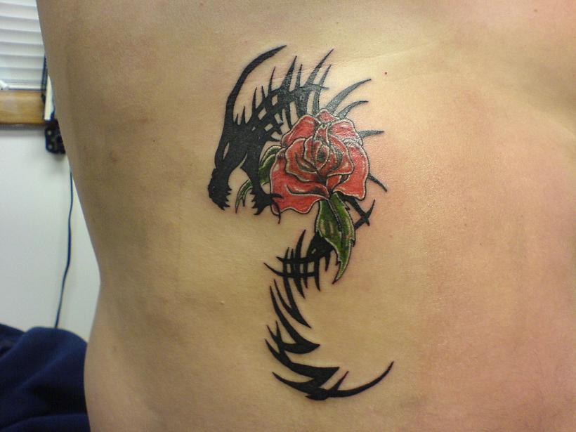 Short haired blonde female with blue rose, heart, and dragon tattoo on her 