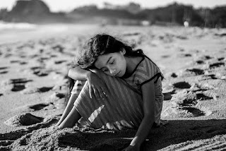 An image of a very sad girl child sitting on the beach- sad girl dp