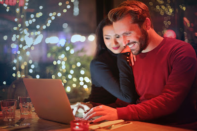 Pareja sonriendo y mirando la pantalla de un portátil