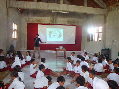 Masih ditahun yang sama 2009, kali ini aku bersama teman-teman Association of Library University Students (ALUS) diminta para kakak angkatan untuk mengisi agenda KKN-nya di SD Petinggen, Yogyakarta. Kami disuruh mengenalkan perpustakaan ke siswa SD kelas 2 dan 3. Rencananya akan ada dua kelas yang kami isi, sehingga kami sudah berbagi tugas siapa yang mengurusi kelas 2 dan kelas 3. Sesampai dilokasi, ternyata dari pihak sekolah menawarkan agar mereka digabung menjadi satu. Biar lebih fokus dan dapat berkumpul bersama, akhirnya terpaksa aku sendiri yang memberikan materi dan teman-teman yang lain mengkoordinasi siswa dan mengisi permainan disaat waktu senggang. Kali ini untuk anak SD aku mengambil tema tentang Perpustakaan, apa itu Perpustakaan dan kenapa kalau disekolah harus ada Perpustakaan. Cukup menarik sih kalau mendengar pernyataan siswa-siswa SD mengenai apa itu perpustakaan. Bahkan salah satu diantara mereka ada yang bilang “Perpustakaan itu kelasnya buku”. Mungkin karena yang didalamnya hanya ada banyak buku dan satu orang staff dikira guru sama mereka. Tapi yang membanggakan adalah mereka sangat antusias mengikuti dan aktif bertanya, bahkan seseorang siswa berani berbagi pengalaman ketika masuk ke perpustakaan. Dan yang menggembirakan lagi adalah saat aku Tanya “Suka baca buku nggak sih?” Kompak banget pada bilang “Suka!!!”. Ditambahin lagi bilang “Saya suka baca komiknya kak, buku cerita rakyat kak” Hemmm, banyak banget jawaban-jawaban dari mereka. Dari sini aku merasa apa yang aku dan teman-teman lakukan selama ini tidaklah sia-sia. Aku bisa memberika sebuah motivasi bagi mereka walau hanya sebentar. Mungkin mereka melupakannya kelak, tapi aku percaya mereka pasti akan mengingat kembali apa yang telah kami lakukan saat ini. Kami percaya bahwa siswa-siswa di Indonesia tidaklah malas membaca, hanya saja fasilitas yang ingin mereka pergunakan sangat kurang. Dan itu adalah salah satu penyebab kenapa siswa kita dikira minat bacanya rendah. 