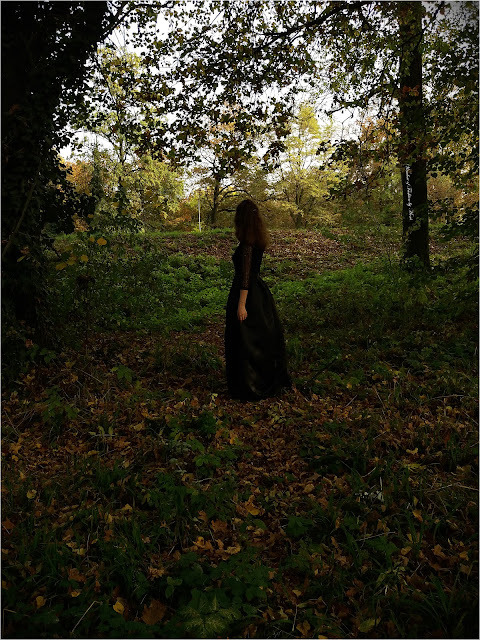 Dziewczyna w długiej czarnej sukni w ciemnym lesie