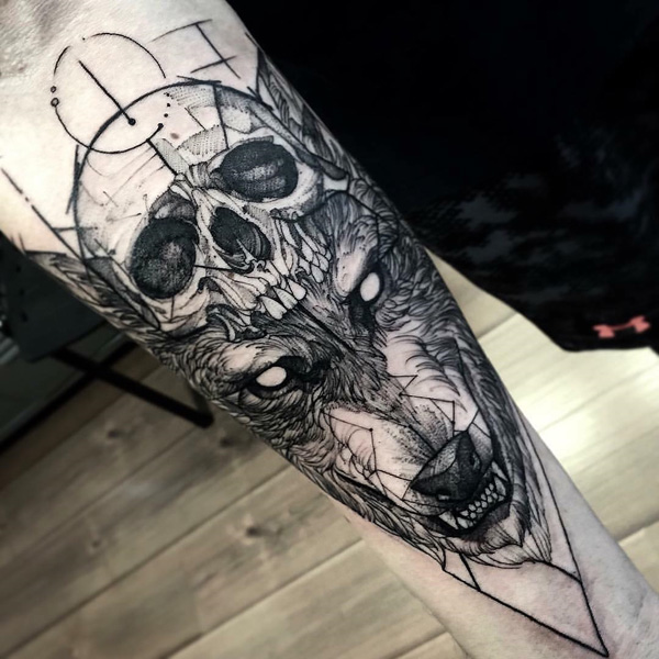 Um crânio e o lobo temáticos manga da tatuagem. Você pode ver o crânio humano que está sendo usado como um chapéu pela raiva olhando lobo. A tatuagem parece bem feito e destemido e definitivamente não é para os fracos de vontade.  