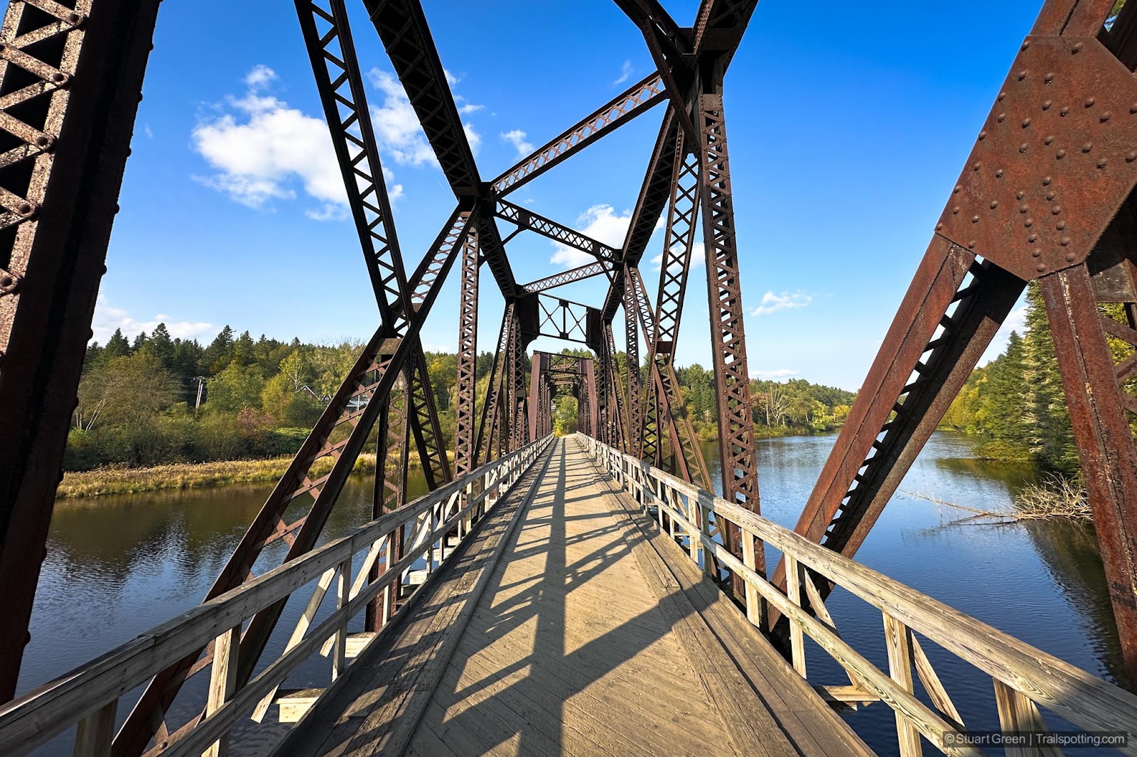 Large two-span steel truss bridge across the Connecticut River. Exposed surface is a rusty red.