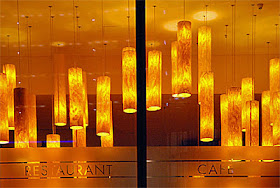 orange lamps hanging in restaurant viewed through window 
