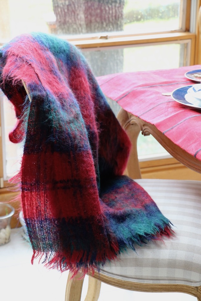 Red, green, and blue jewel plaid colors of a mohair throw on a French Country dining chair goes with the tablecloth on the Christmas Red and Navy Blue Table Setting