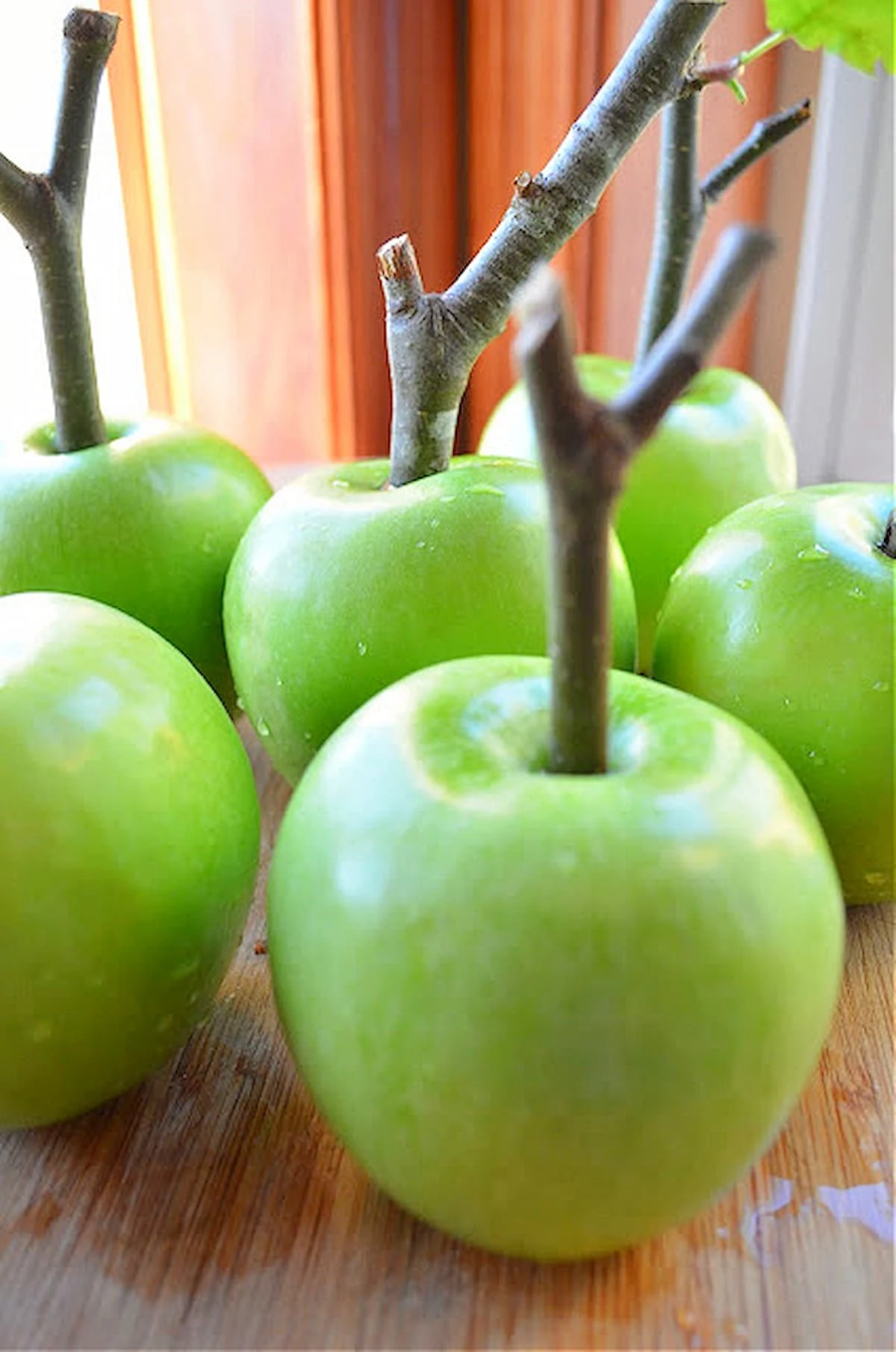 Apples with a Apple Twig in the center on a wooden cutting board.