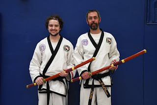 Two black belt tournament grand champs holding their sword trophies
