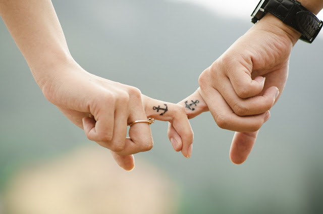 Photo showing a love between husband and wife while they hold each others finger