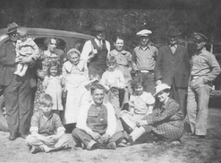 Group photo of family standing in front of old car during camp meeting from 1930's or 1940's