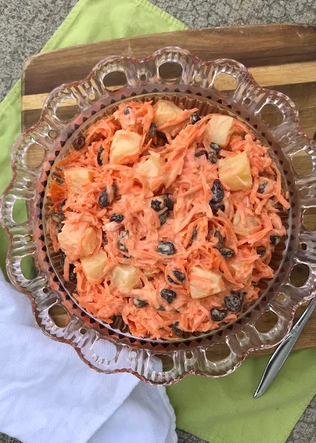 Serving bowl full of creamy carrot, raisin, and pineapple salad.