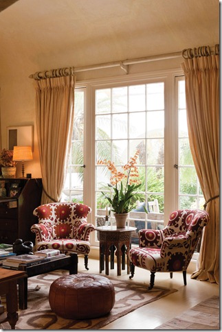 Pair of matching armchairs upholstered in Kathryn Ireland fabric and moroccan leather pouffe in living room with coved ceiling