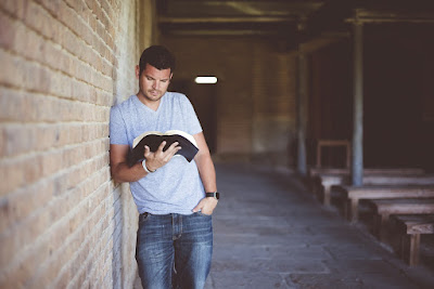 Man reading against brick wall