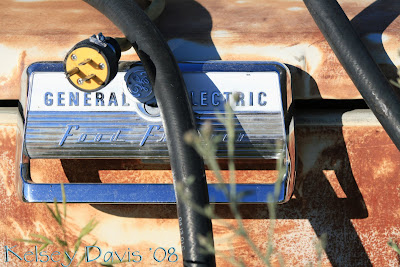 Rusted General Electric Freezer with bright crome handles in the middle of a field