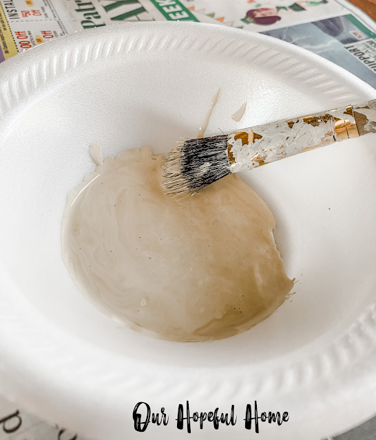 styrofoam bowl filled with brownish paint and paint brush