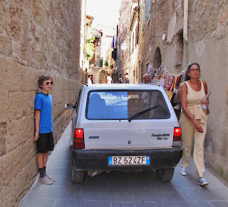 Driving down narrow streets in historic centre of Tuscan villages, Cortona, Italy