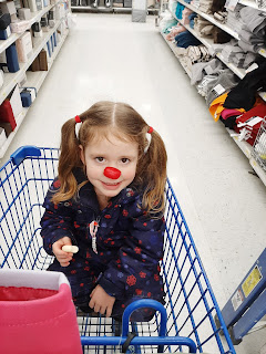 Ellie sits in cart with red babybel nose