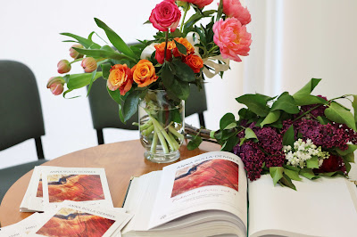 ksiąga pamiątkowa, foldery leżą na stoliku, obok leżą kwiaty i w wazonie kwiaty