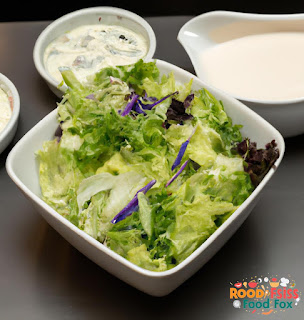 A bowl of salad with creamy lemon dill dressing on top.