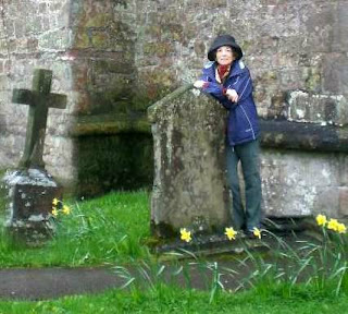 a photo of author Donna Fletcher Crow researching a story in Wales. She is standing among tombstones.