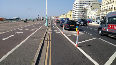 A view of the cycle lane with a parking bay to the right, plus the wide pavement with an oncoming cycle track on the left.