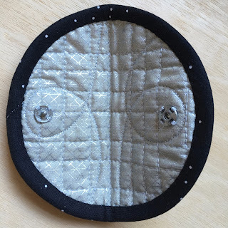 inside of quilted circle with snap fasteners sewn on either side below binding